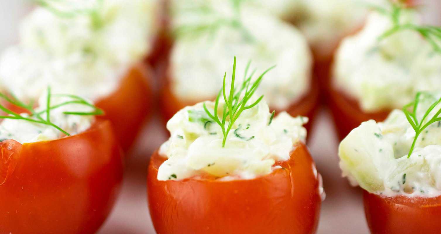 Tomatoes hollowed and filled with a creamy cheese mixture, topped with sprigs of fresh dill.