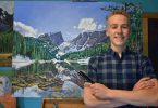 Cody Oldham stands in front of “Arrowhead,” a 36-inch-by-48-inch painting of Hallett Peak.
