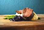 closeup of sous vide steak with blueberry sauce and asparagus