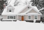 a beige, two-story home surrounded by snow
