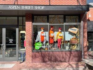 Storefront of Aspen Thrift Shop featuring three dressed mannequins in an autumn-themed window display with a "Finish" sign.