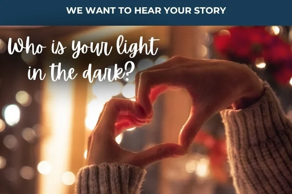 Two hands form a heart shape in front of blurred lights with text that reads, "Who is your light in the dark?" and "We want to hear your story.